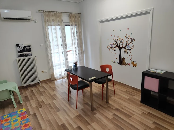 Αίθουσα θεραπείας με διακοσμητικό δέντρο στον τοίχο και παιδικό εξοπλισμό